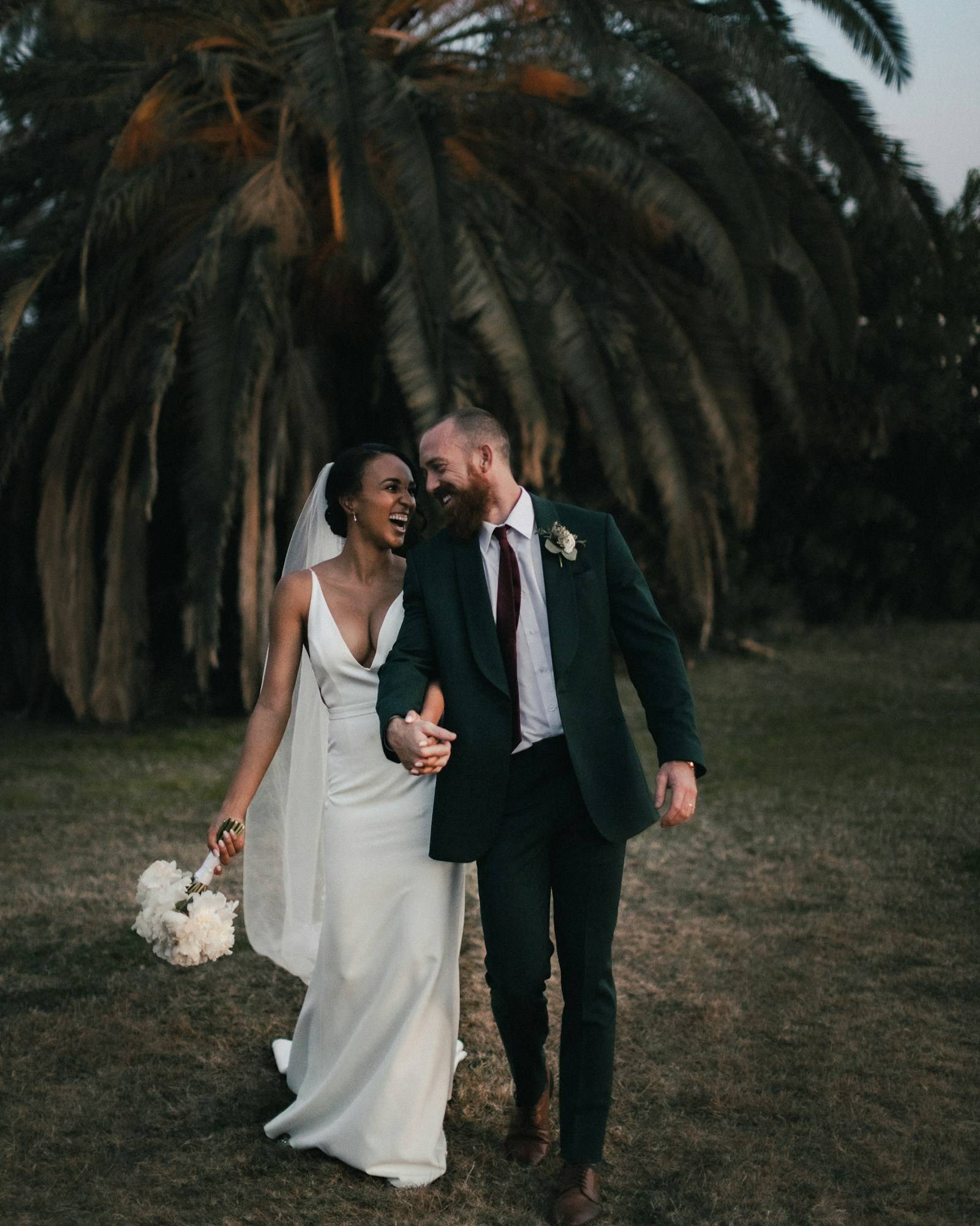The couple walking through a field in the evening light